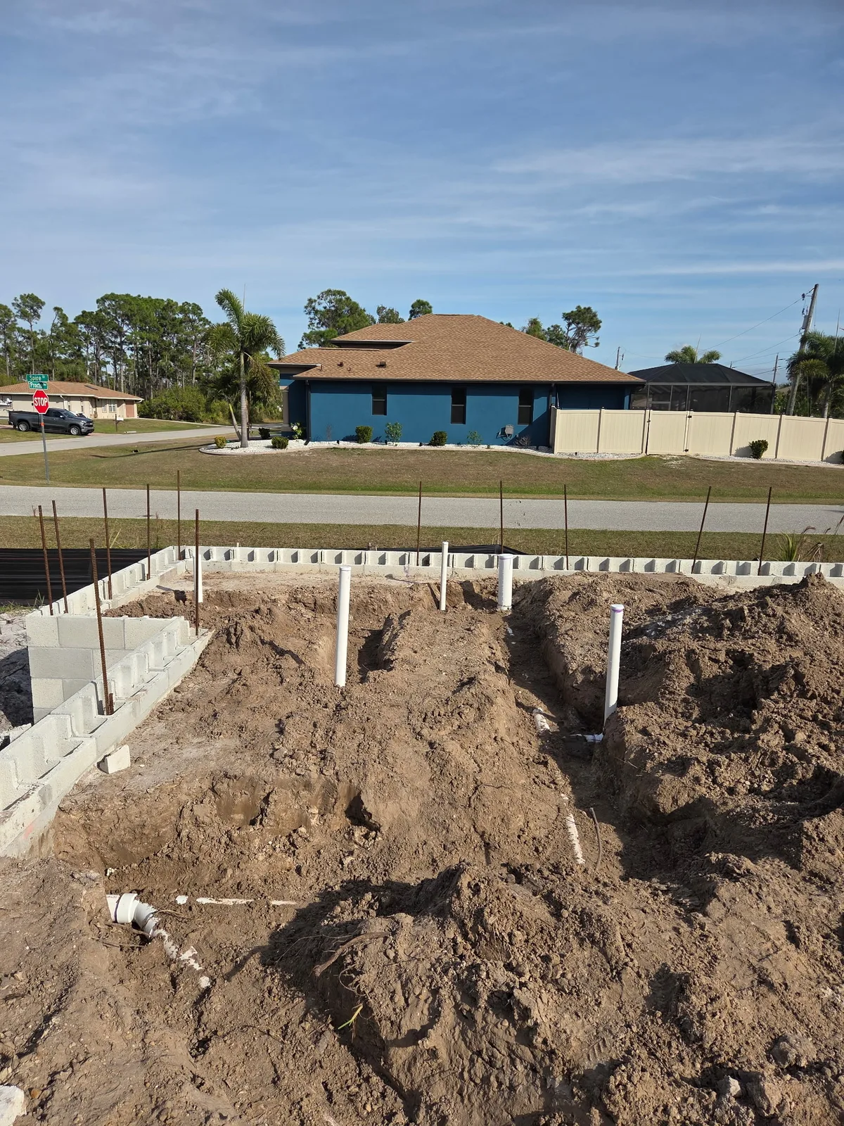 Concrete block stem wall foundation with vertical PVC plumbing stubs on a cleared lot